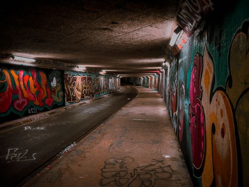 Free A dimly lit underground tunnel in Nieuwegein with vibrant graffiti art on the walls. Stock Photo