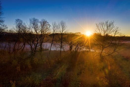 A breathtaking sunset over bare trees in Kellogg, Minnesota, highlighting nature's beauty.