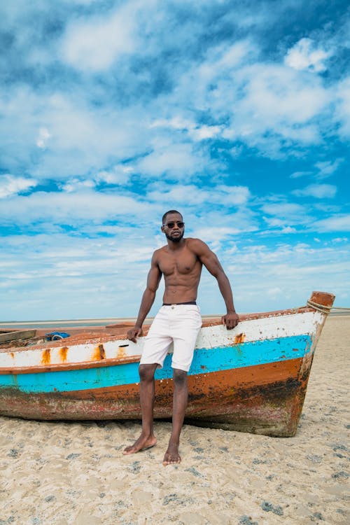 Free Man in White Shorts Standing on Brown Wooden Boat Under Blue and White Cloudy Sky during Stock Photo