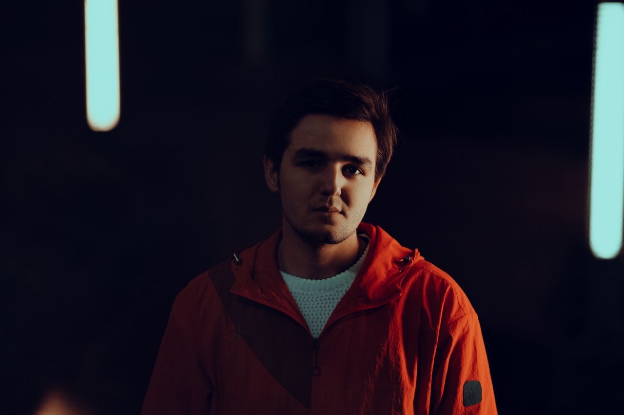 portrait of a young man in a red jacket with moody lighting and blurre