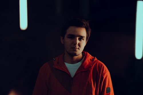 Free Portrait of a young man in a red jacket with moody lighting and blurred background. Stock Photo