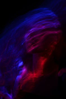 Colorful abstract portrait of a woman with blurred motion and light trails on a black background.