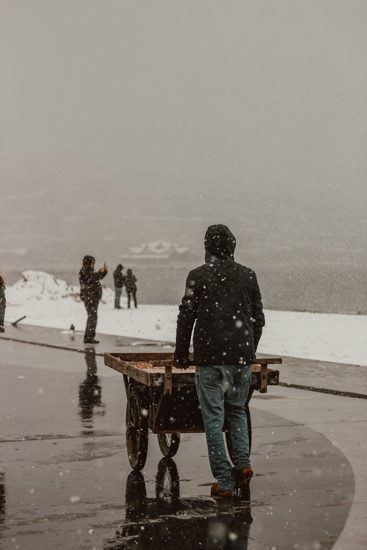 A Back View Of A Person In Black Hoodie Jacket Pushing A Cart