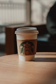 A disposable coffee cup on a wooden table in a cozy indoor setting in Turkey.