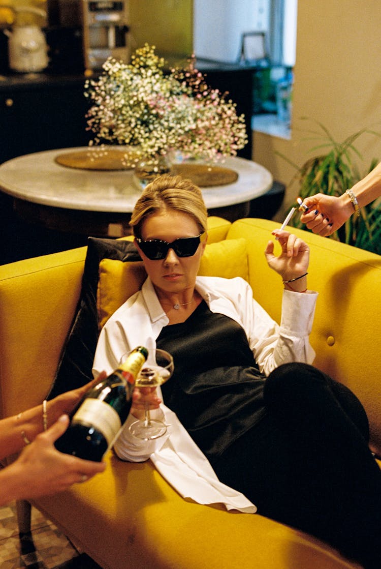 Blonde Woman Lying On Sofa With Wineglass In Hand