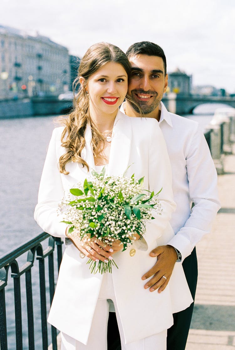 Man Standing Close Behind Woman With Hand On Her Hip And Both Smiling