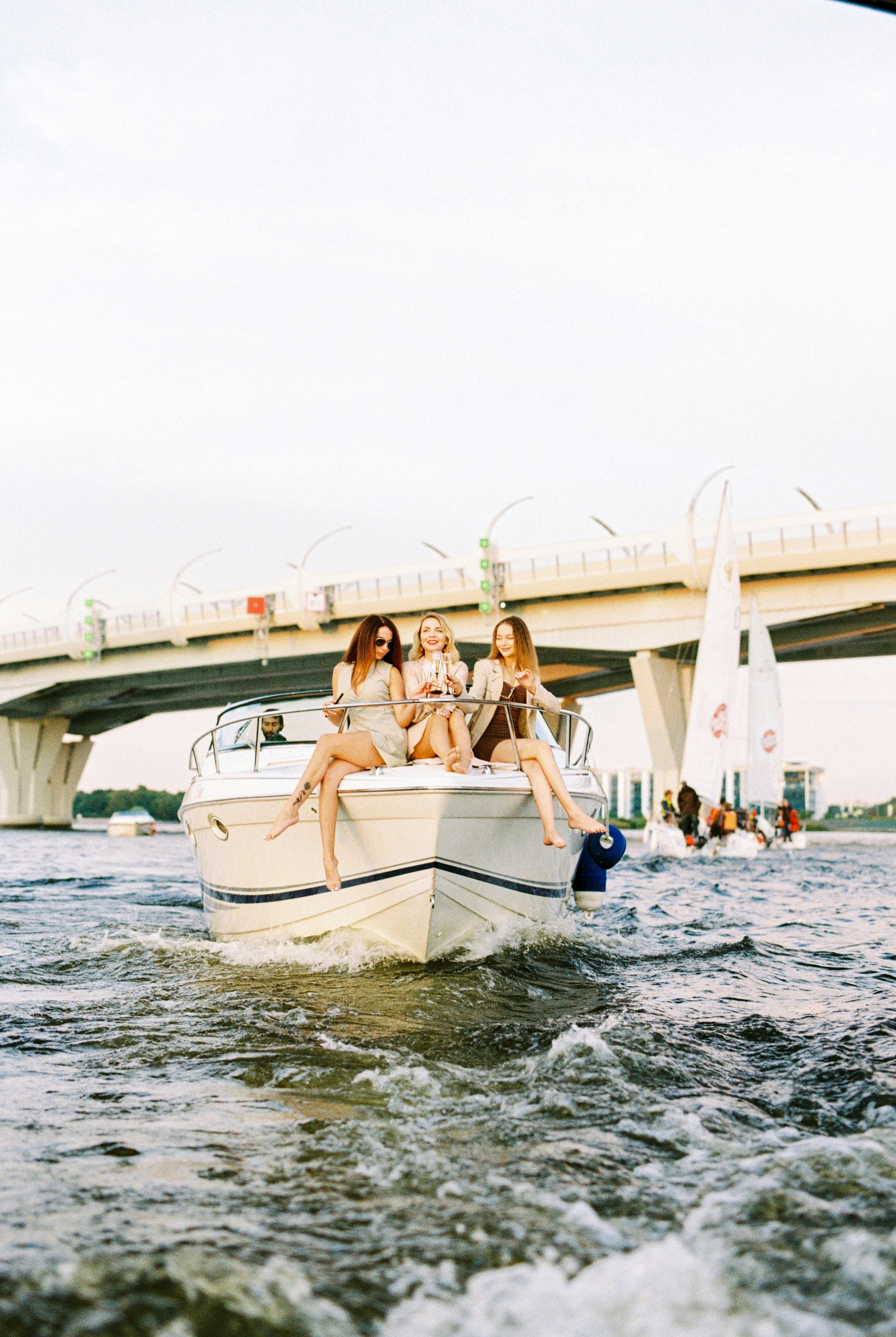 women sitting on flowing motorboat bow and chatting