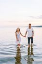 Couple Walking out of Water Holding Hands