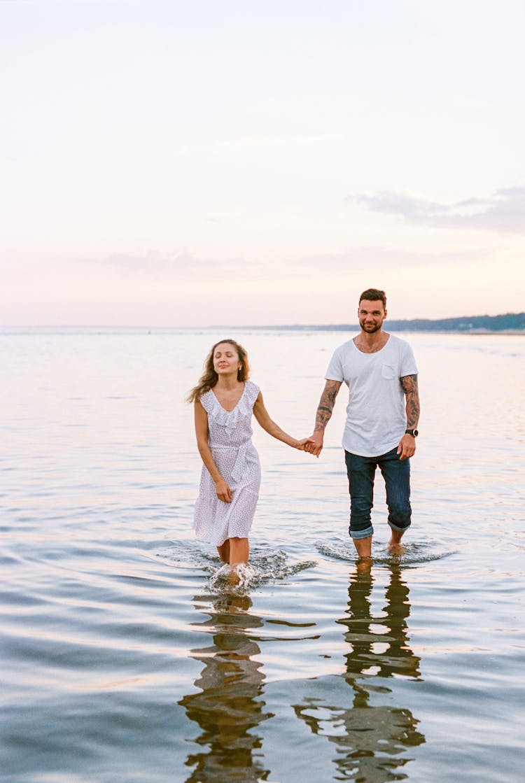 Couple Walking Out Of Water Holding Hands