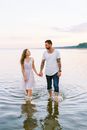 Couple Walking out of Water Holding Hands