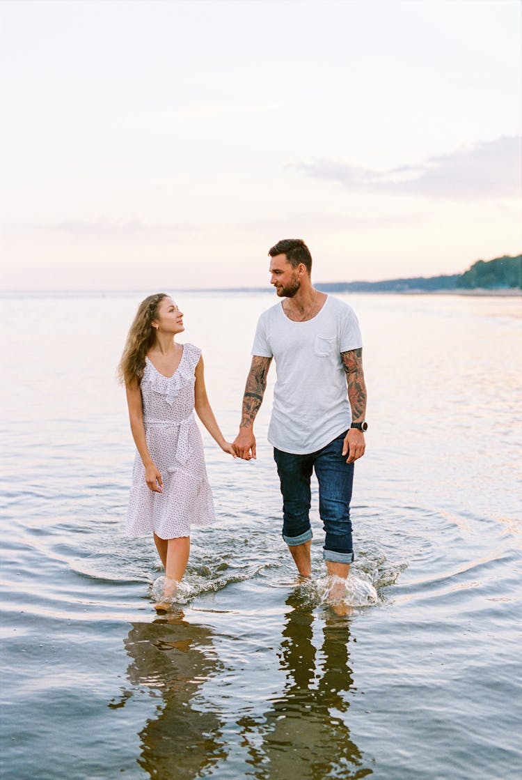 Couple Walking Out Of Water Holding Hands