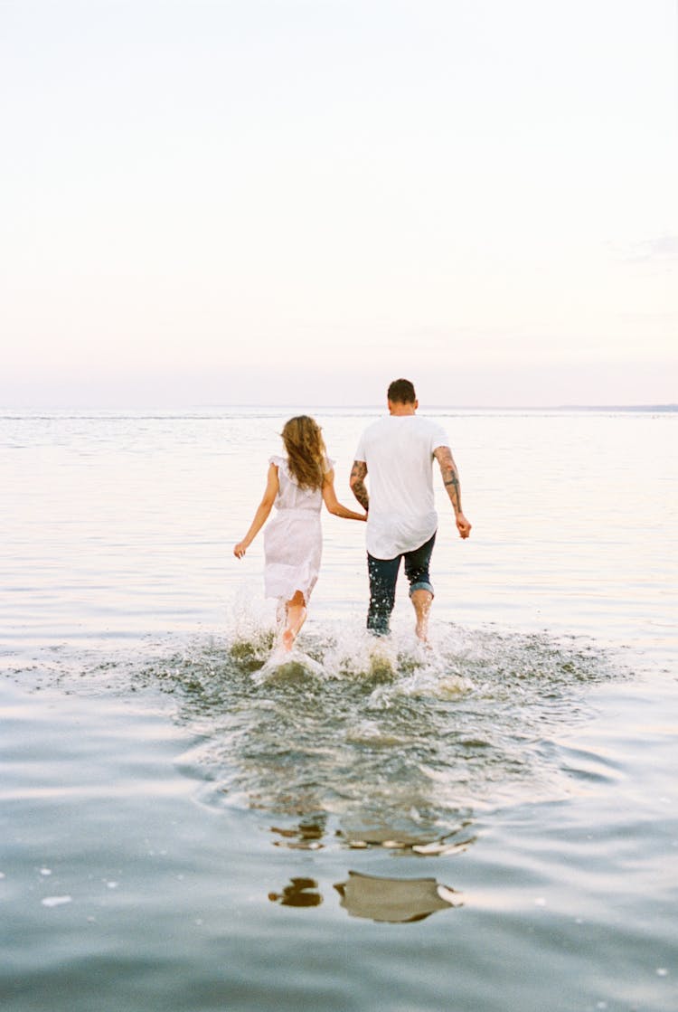 Back View Of Couple Running In Water