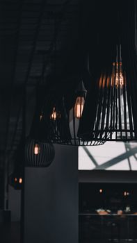 Dimly lit indoor setting featuring elegant ceiling lamps with glowing vintage bulbs casting ambient light.