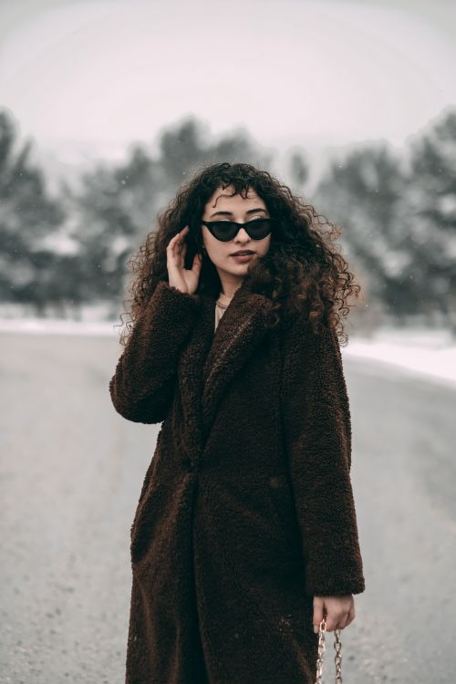 Free Fashionable woman in sunglasses and fur coat standing outdoors on a snowy winter day. Stock Photo