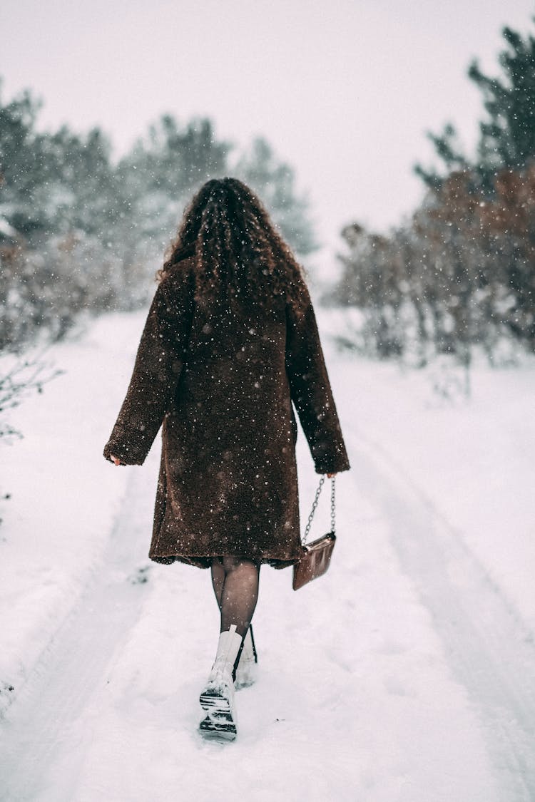 Woman Walking On Snow Covered Road