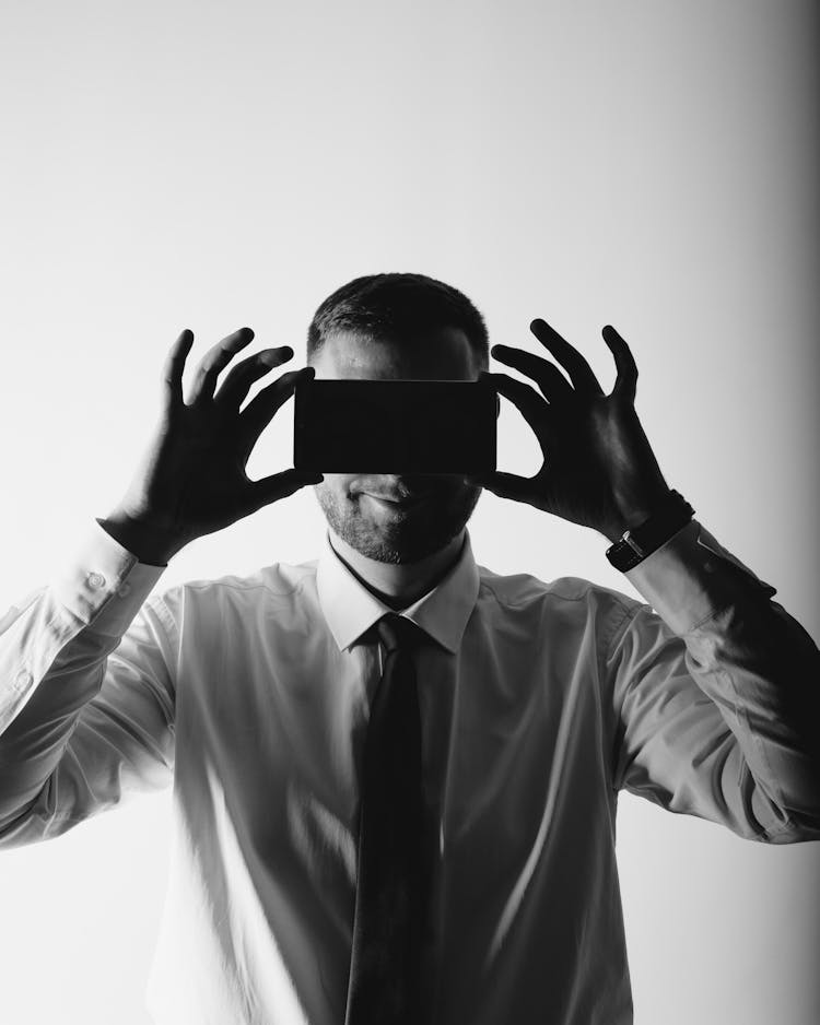 A Man Covering His Eye While Holding A Rectangular Object