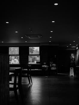 A monochrome view of an empty coffee shop interior with chairs and tables.