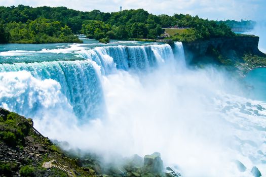 Breathtaking aerial view of cascading waterfalls at Niagara Falls surrounded by lush greenery.