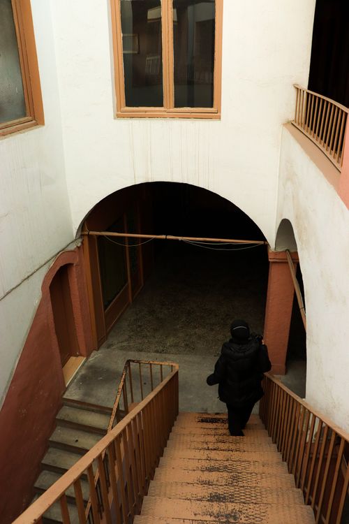 Free A woman in a black coat descends a stairway in a historic building in İstanbul. Stock Photo