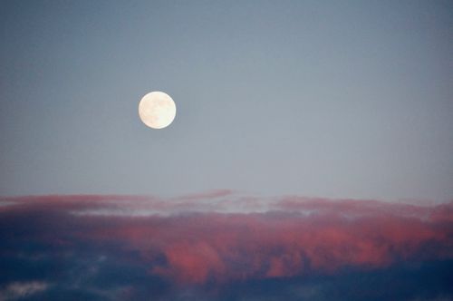 Free A serene view of the full moon against a backdrop of pink clouds at evening twilight. Stock Photo