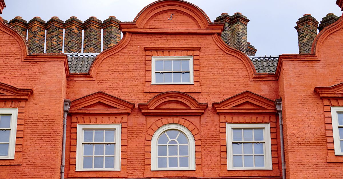Front view of a vibrant orange brick building facade with classic windows.