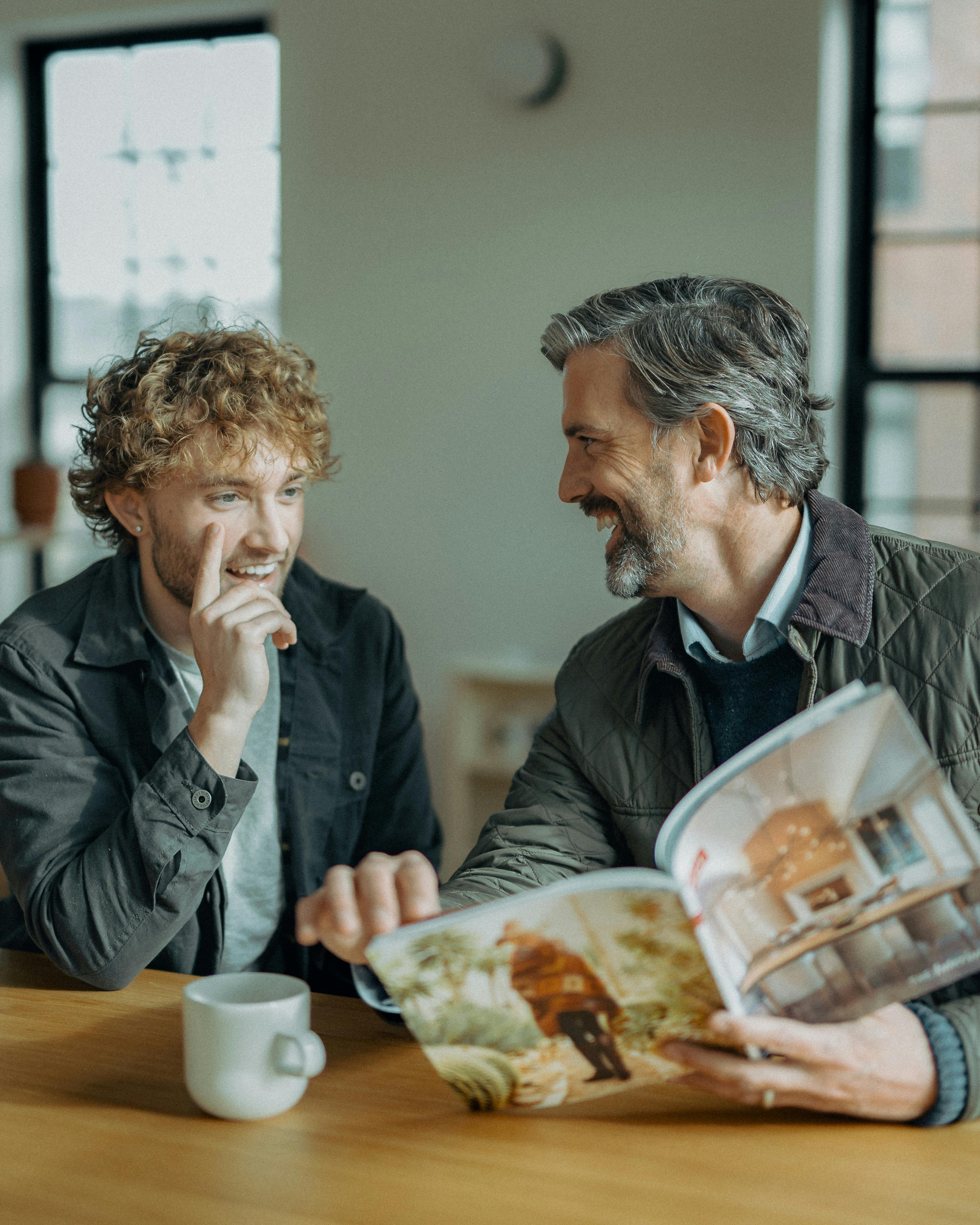 Two Men Sitting and Laughing at a Table · Free Stock Photo