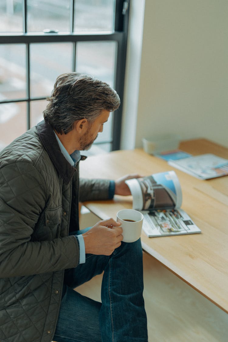 A Man Looking Through A Brochure At His Desk 