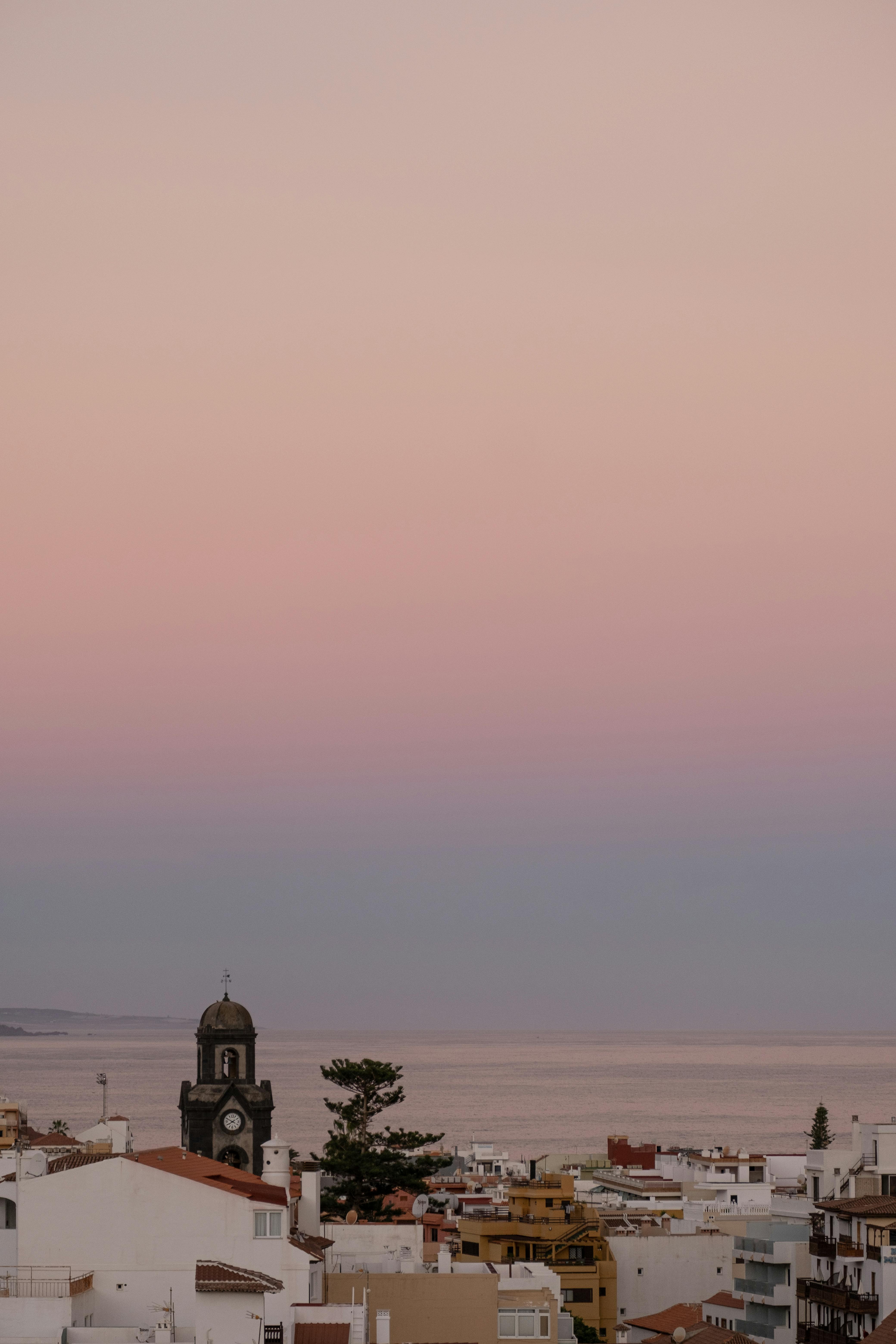 Scenic view of coastal town against a serene sunset sky over the ocean.