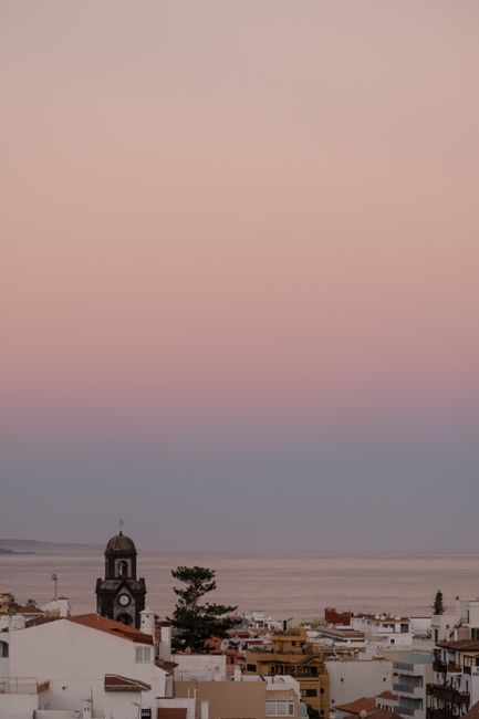 Scenic view of coastal town against a serene sunset sky over the ocean.