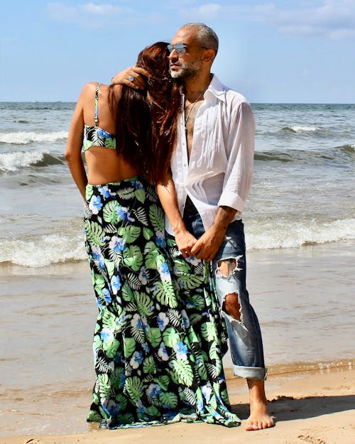 A Man and Woman Standing on the Beach Sand while Embracing Each Other