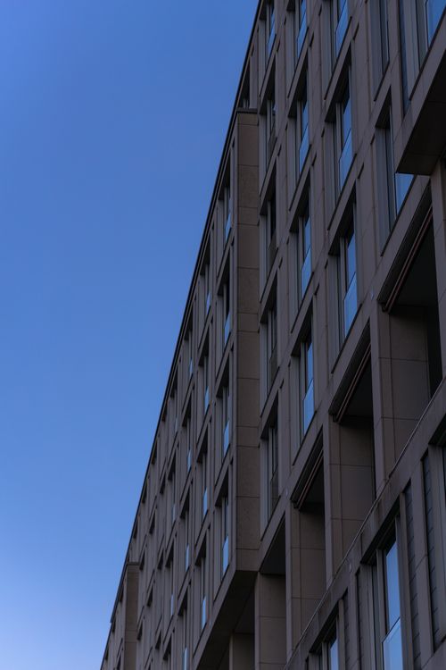 Free Low-angle view of a modern concrete building against a clear blue sky in Berlin, showcasing contemporary architecture. Stock Photo