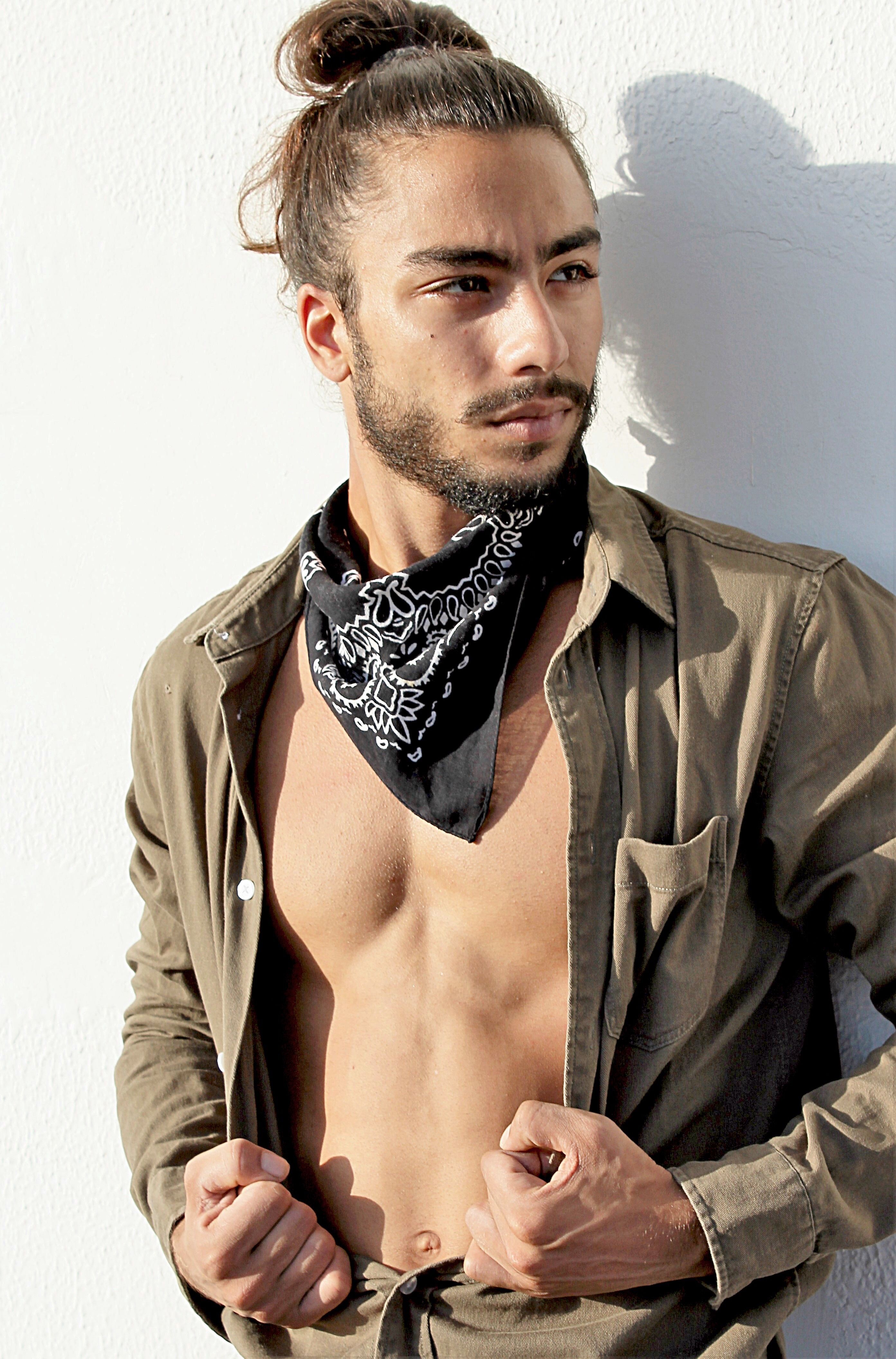 Portrait of a stylish man wearing a bandana and open shirt, exuding confidence and trendiness.