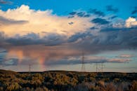 自然景观中，戏剧性的天空、彩虹与电力线交相辉映