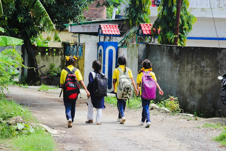 A Group Of Friends Walking On The Street While Carrying Their Backpacks