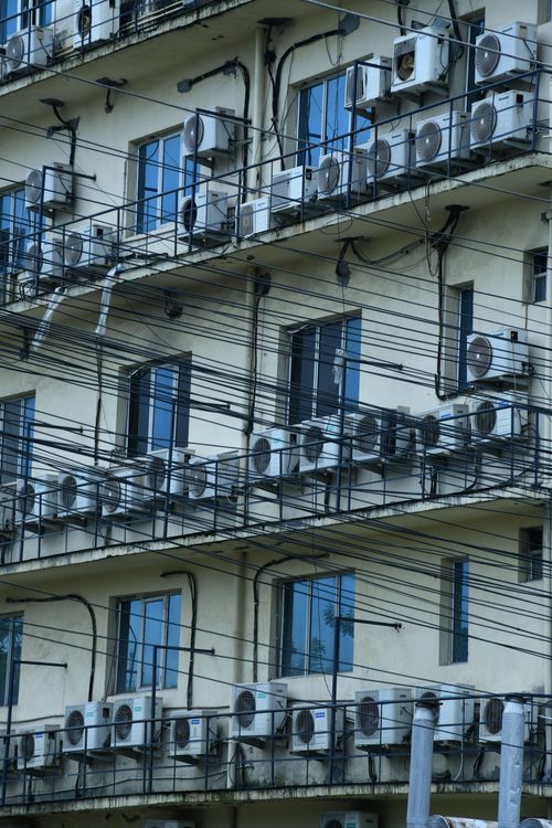 Free Facade of an urban residential building with multiple air conditioners and balconies. Stock Photo