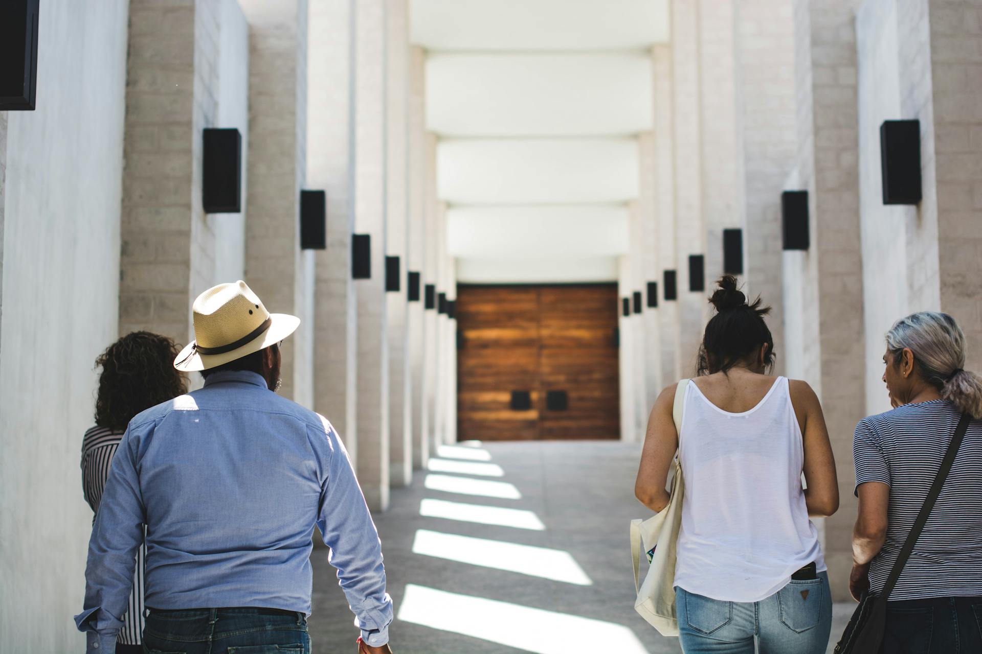 People strolling in a sunlit architectural corridor, showcasing modern Mexican design.