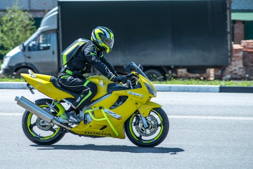 Person in Black Motorcycle Suit Riding Yellow Sports Bike