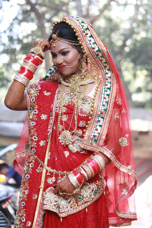 Free Beautiful Indian bride wearing traditional red attire with intricate jewelry and henna design. Stock Photo