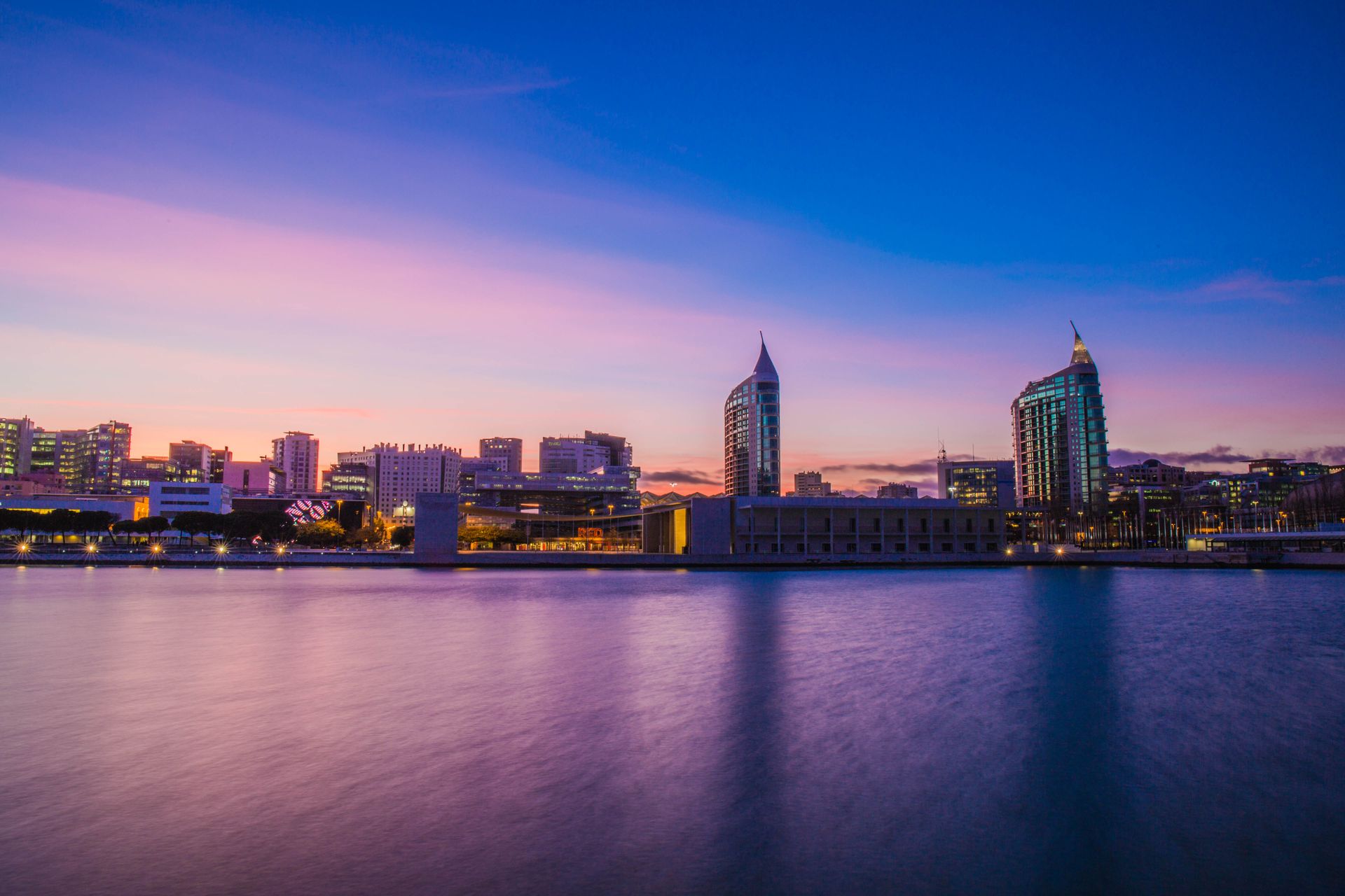 Beautiful cityscape of Lisbon at dusk featuring modern architecture and waterfront view.