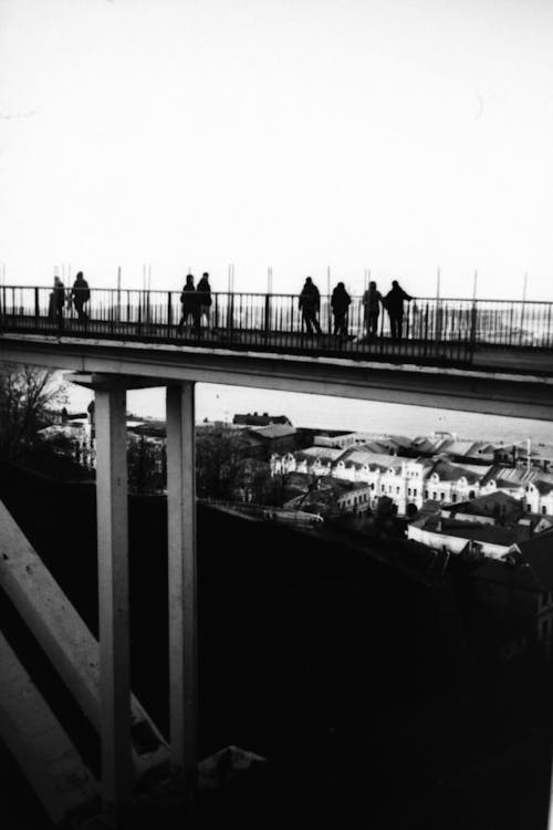 Grayscale Photo of People Walking on Footbridge