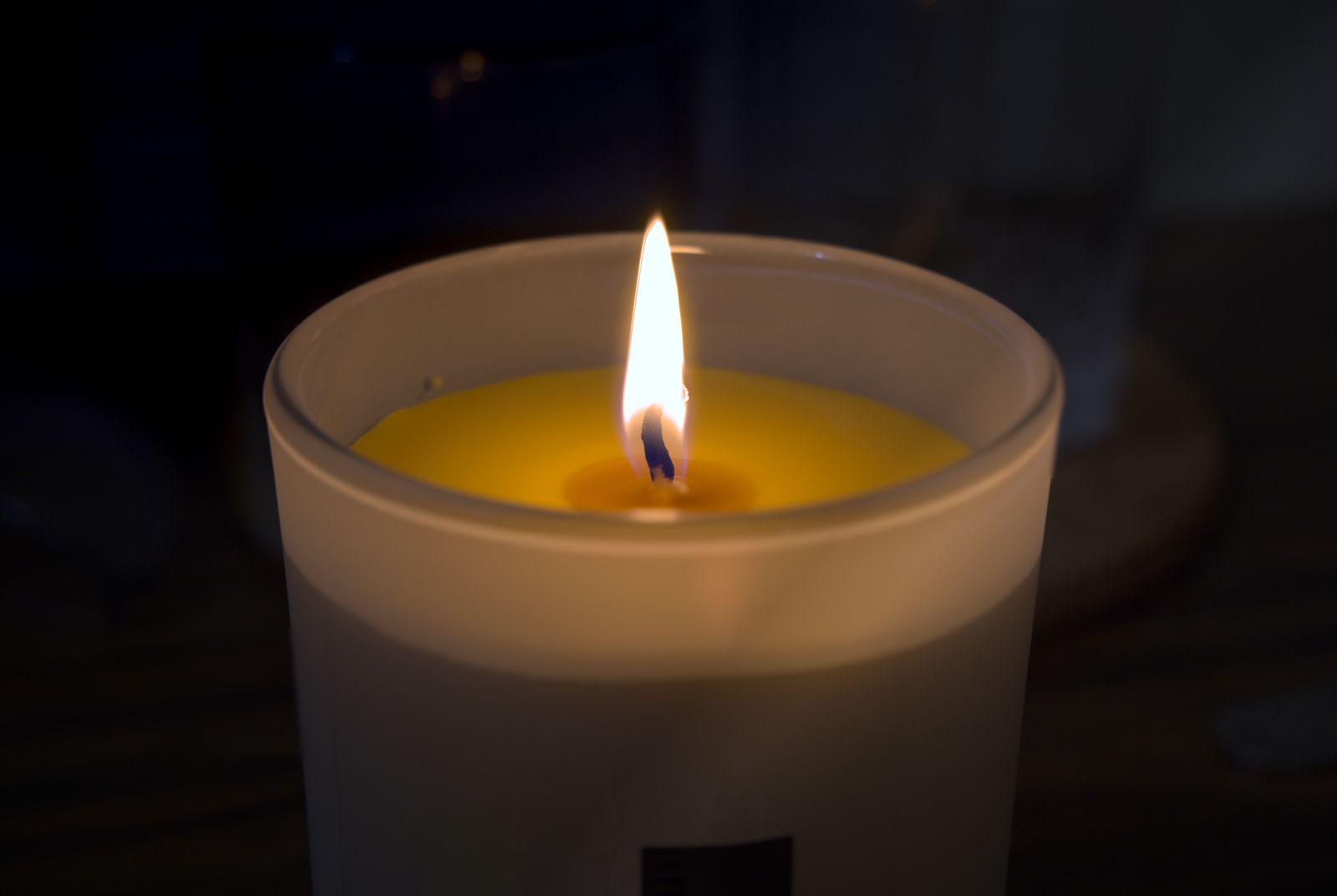 Bougie allumée à la cire jaune dans un pot en verre dépoli