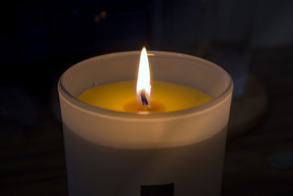 Bougie allumée à la cire jaune dans un pot en verre dépoli