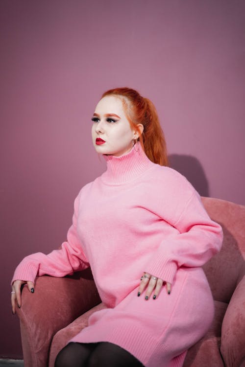 A Redheaded Woman in Pink Dress Sitting on a Sofa