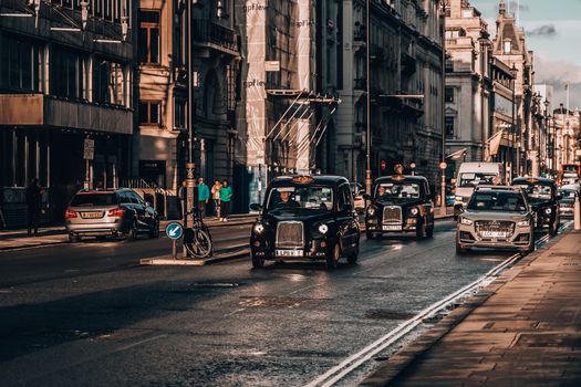 Urban street scene in London featuring classic black cabs and historic architecture.