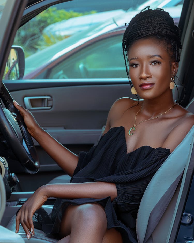 A Woman In Black Dress Sitting Inside A Car