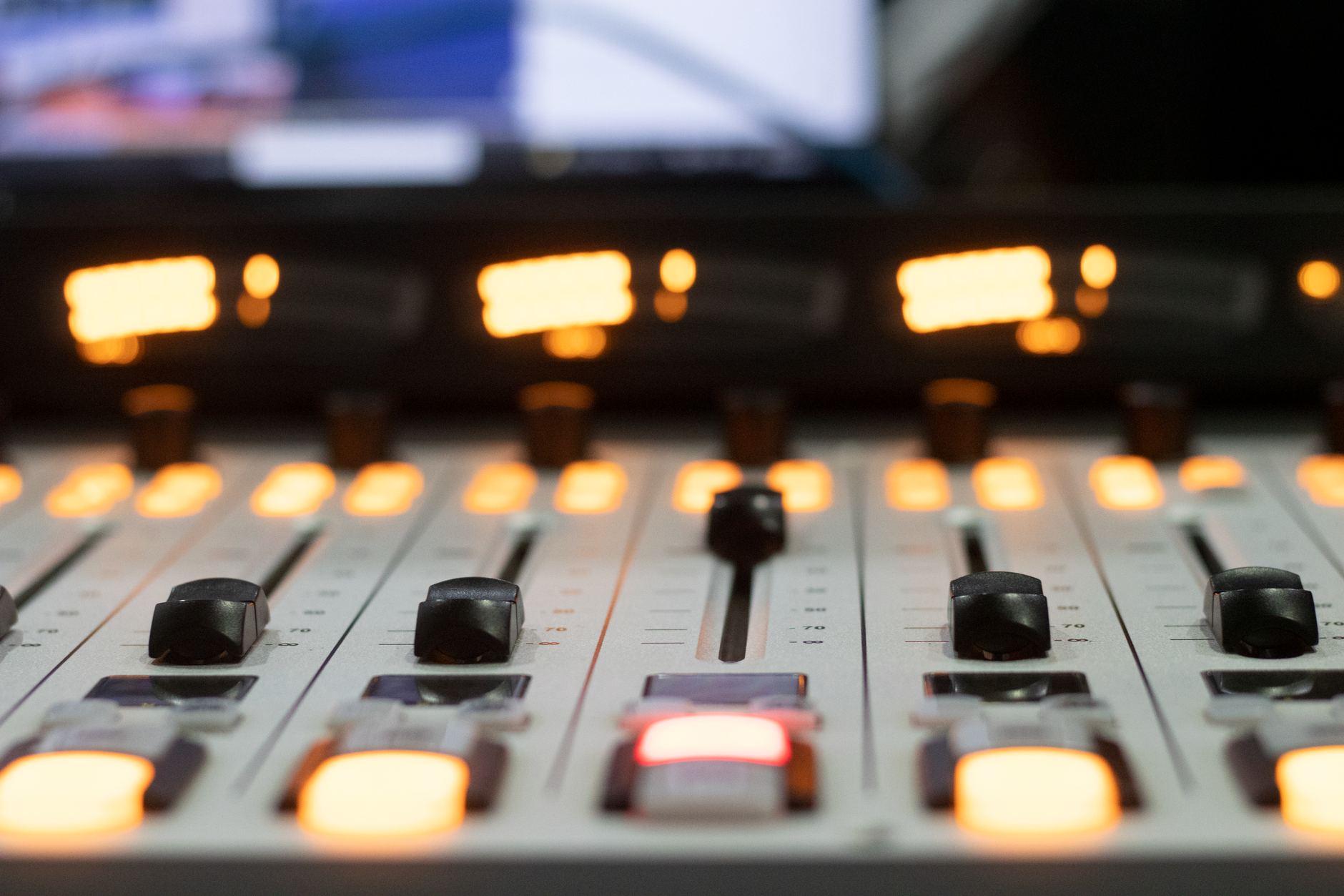 Detailed view of a professional audio mixing console with illuminated sliders and buttons.