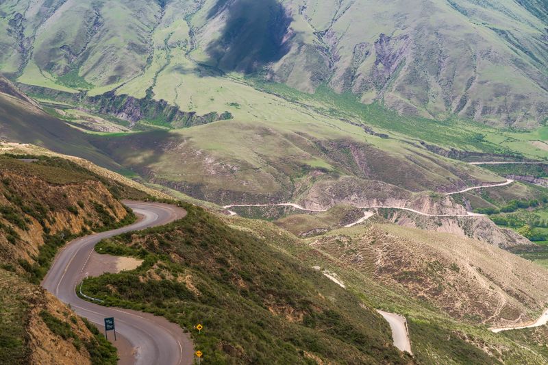 Aerial view of winding roads through green mountains — photo by Hector Perez on Pexels