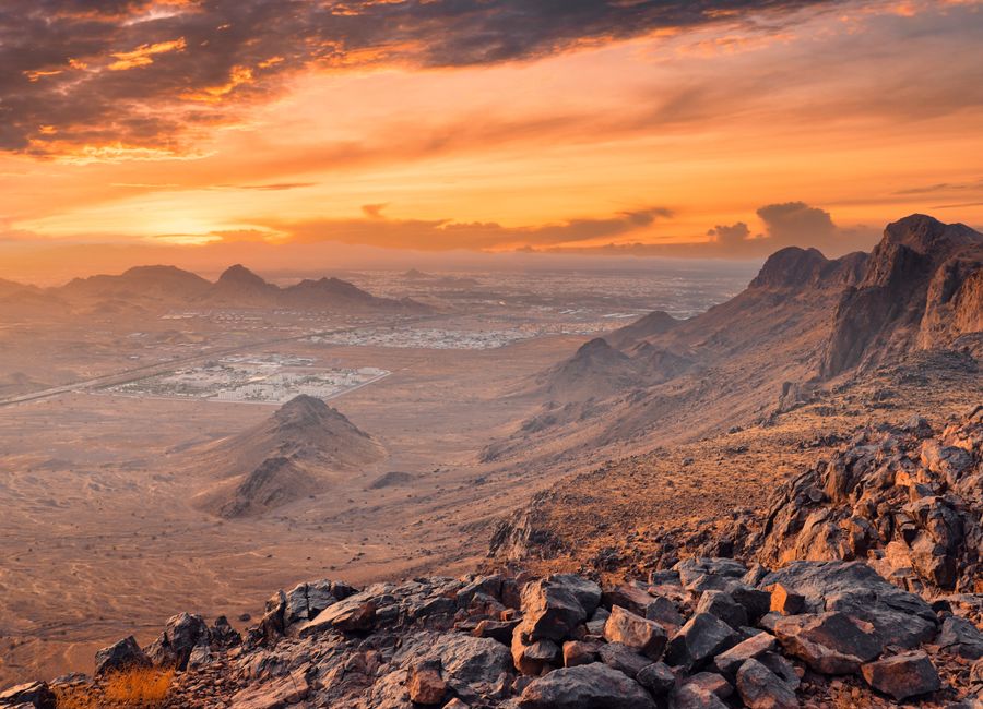 Panoramic view of rocky desert landscape in Medina, Saudi Arabia at sunset, showcasing vibrant sky and mountains.