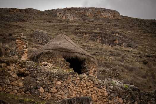 A traditional stone hut with a thatched roof in the highlands of Peru.