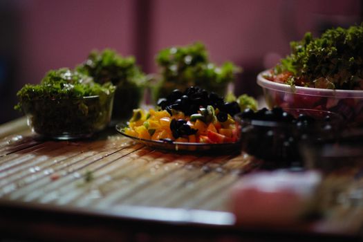 Vibrant vegetable salad arrangement with fresh greens and olives on a rustic wooden table.